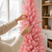 Hands fluffing the branches of the pink pencil Christmas tree