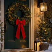 Red velvet bow on a pine wreath on a front door at Christmas