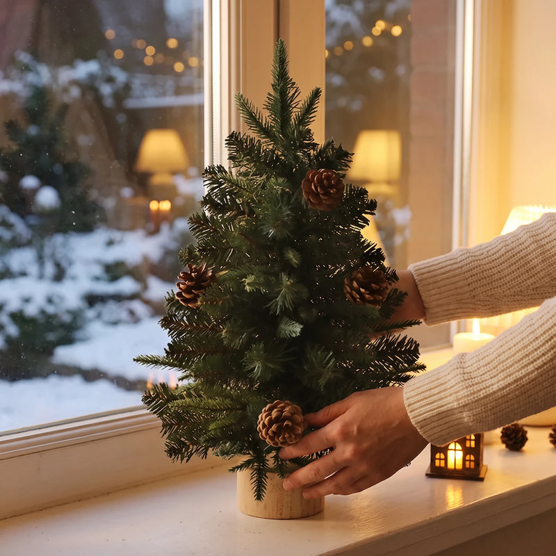 Hands placing the mini Christmas tree on a snowy windowsill