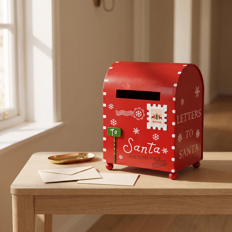 Red Christmas mailbox on a wooden console with blank envelopes in a warm entryway