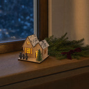 Style A wooden LED Christmas village house glowing on a wooden window ledge at blue hour