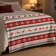 Fair isle Christmas throw at the foot of a bed in a bedroom lit by a warm bedside lamp