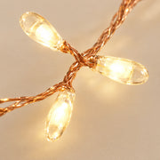 Close-up of glowing teardrop LED beads on a copper wire light string