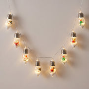 Snow globe Christmas bulb string lights hanging in a warm white arc against a pale wall