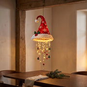 Illuminated Santa hat decoration beside a dining table in an evening interior.