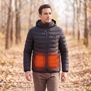 Black hooded heated jacket worn outdoors with schematic red-orange lower-front heating zones based on the supplier illustration; not a thermal measurement