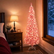 Lit pink pencil Christmas tree in the corner of a bedroom in the evening