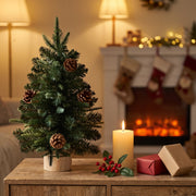 Mini Christmas tree on a wooden sideboard next to a candle and wrapped gifts
