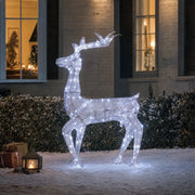 Silver light-up deer glowing cool white in a snowy garden at night