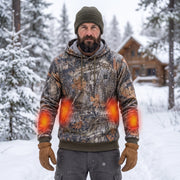 Rugged bearded outdoorsman wearing the woodland camouflage heated hoodie prominently in a snowy pine forest; red-orange zones are illustrative heating overlays.