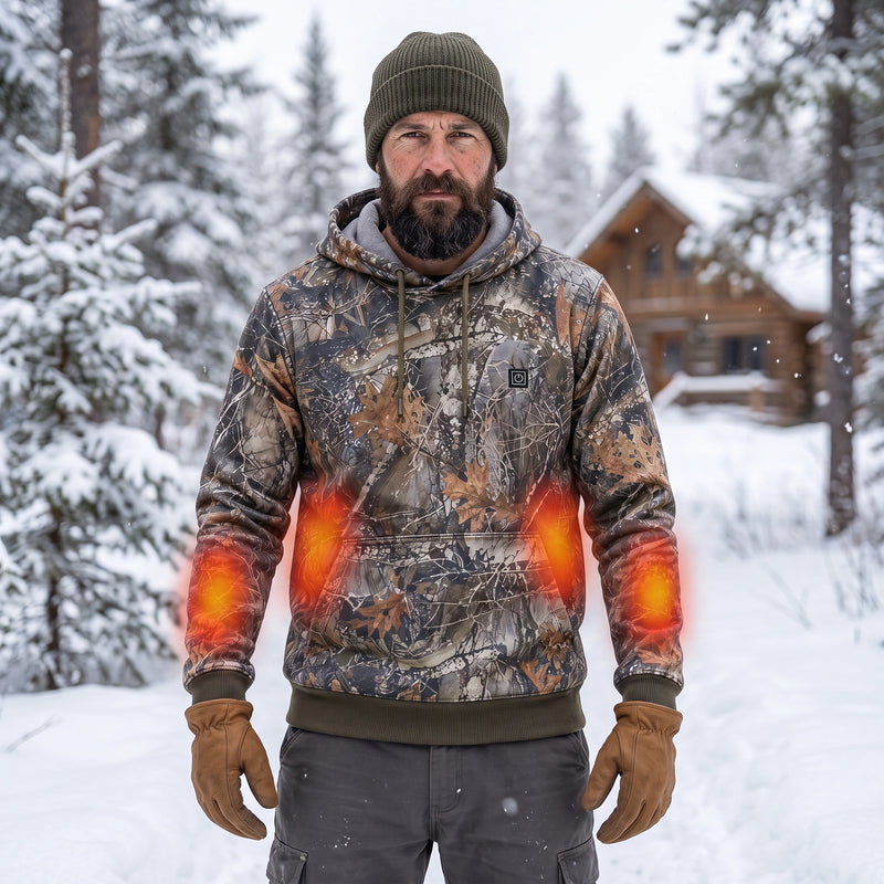 Rugged bearded outdoorsman wearing the woodland camouflage heated hoodie prominently in a snowy pine forest; red-orange zones are illustrative heating overlays.
