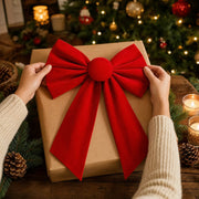 Hands placing a red velvet bow on a kraft paper gift