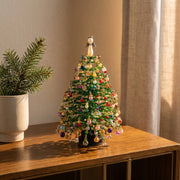 Colorful beaded holiday tree beside a pine branch
