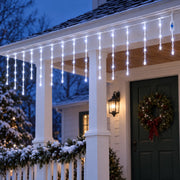 Icicle curtain lights along the eaves of a cottage porch at blue hour
