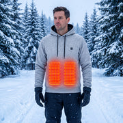 Man wearing the gray heated hoodie in snow, with illustrated front heating zones; red glow is a schematic overlay, not a printed design.