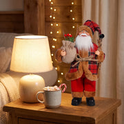 Plaid Santa figurine on a side table beside a glowing lamp and a cup of cocoa