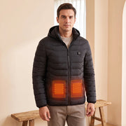 Black hooded heated jacket worn in an entryway with schematic red-orange lower-front heating zones based on the supplier illustration; not a thermal measurement