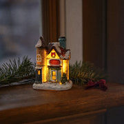 Christmas village house glowing on a wooden window ledge at dusk