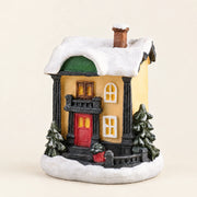Snow-covered resin Christmas village house on a pale cream background