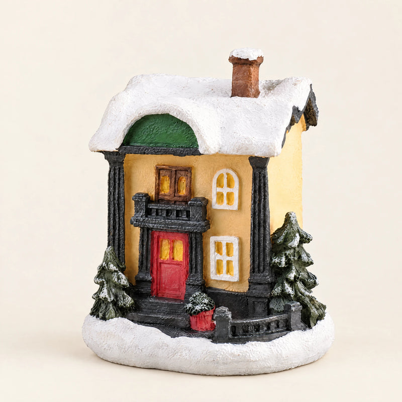 Snow-covered resin Christmas village house on a pale cream background