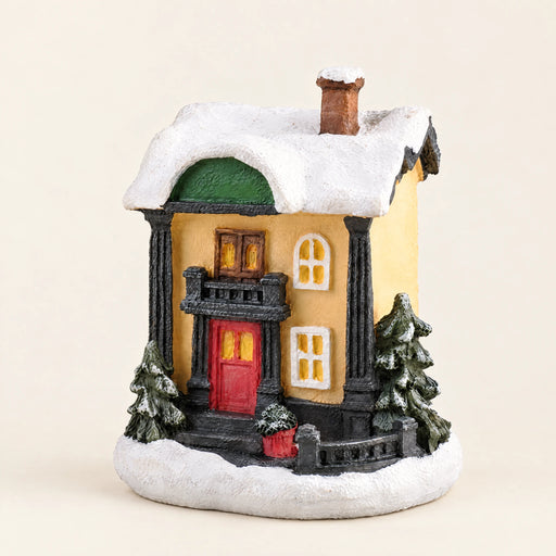 Snow-covered resin Christmas village house on a pale cream background