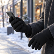 Black winter gloves holding a smartphone in a winter street