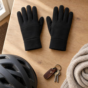 Flat lay of black winter gloves with a bike helmet and a knit scarf