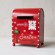 Red metal Christmas mailbox printed with snowflakes and Letters to Santa on a pale surface